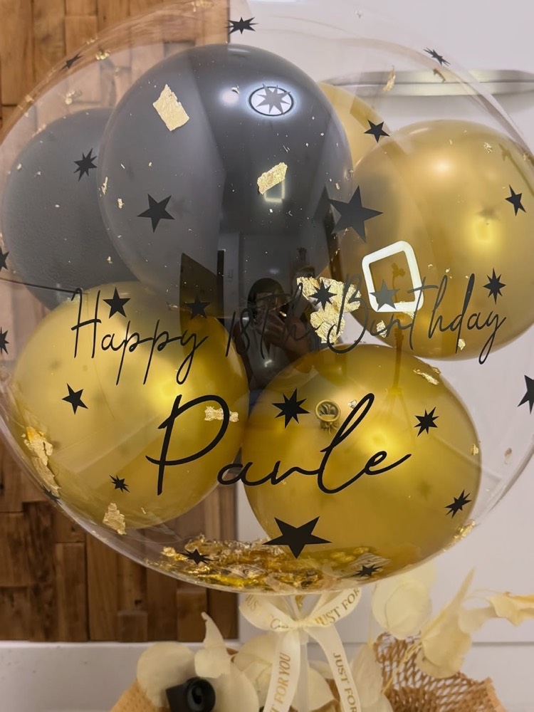 Durchsichtiger Ballon mit Schrift, darum Ballons in Gold und Schwarz