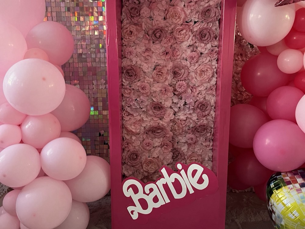 Rosa Ballons und Blumenwand mit Barbie-Schriftzug