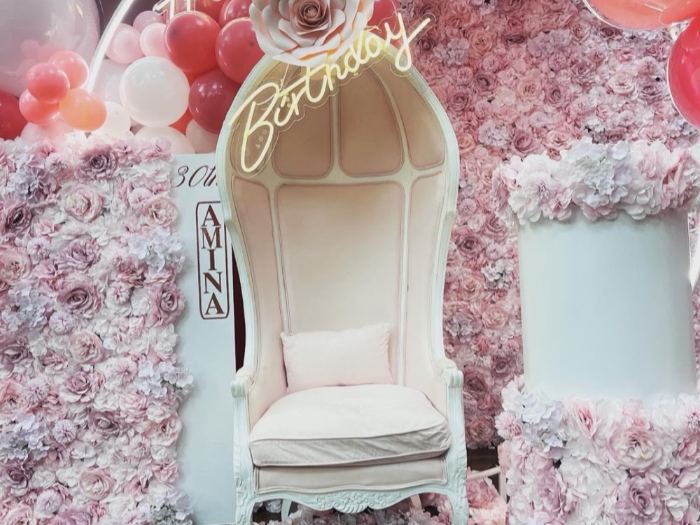 Weisser Thron-Sessel vor einer Blumenwand in Rosa