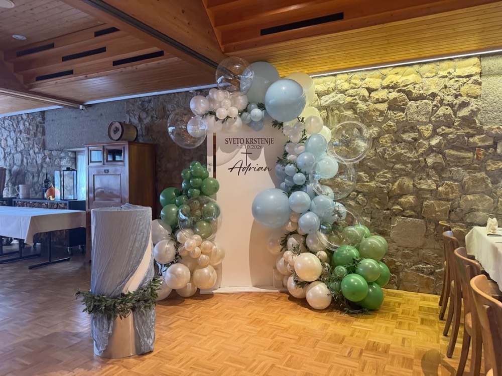 Ballonbogen in Grün, Hellblau und Beige vor einer Steinwand