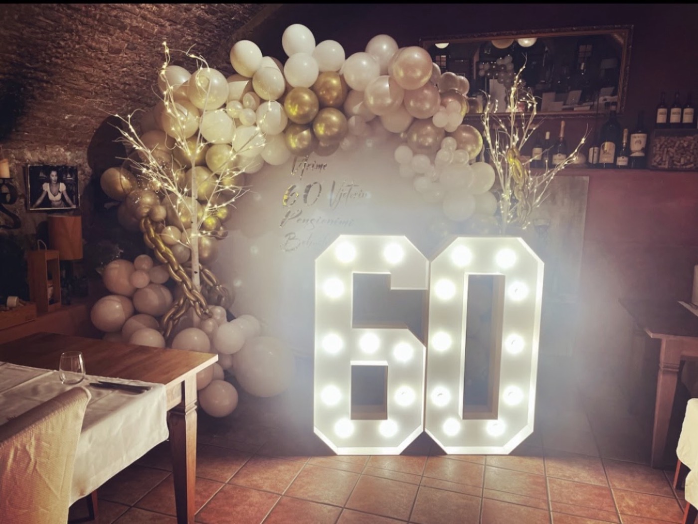 Leuchtzahl 60 vor einem Ballonbogen in Gold und Weiss